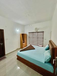 a bedroom with a large bed with blue sheets and a window at Guest arc Residency in Sultan Bathery