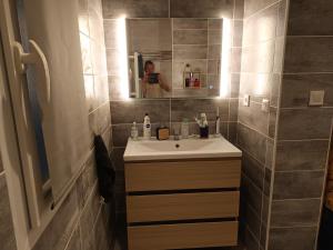 a woman taking a picture of a bathroom with a sink at loue 2 chambres individuellemet chez l hote in Pia +4 photos