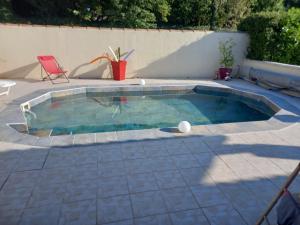a small swimming pool with a red chair in a backyard at Chez Carole et Roger in Avignon +5 photos