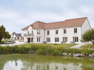 un grand bâtiment blanc avec un étang en face dans l'établissement L'Orée des Châteaux, à Bracieux