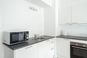 Una cocina blanca con microondas y fregadero. en Beautiful 1-BR w a balcony by Odense harbour - 82, en Odense