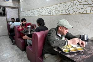 a man sitting at a table with a plate of food at Hotel Bhagirath in Mumbai
