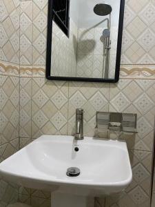 ein weißes Waschbecken in einem Badezimmer mit einem Spiegel in der Unterkunft Nilevic Guest House Entebbe in Entebbe + 23 Fotos