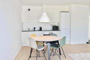 cocina blanca con mesa y sillas en Beautiful 1-BR w a balcony by Odense Harbour - 121, en Odense
