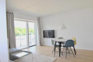 Una sala de estar blanca con una mesa y sillas. en Beautiful 1-BR w a balcony by Odense Harbour - 121, en Odense