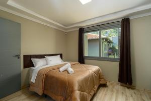 a bedroom with a bed with two towels on it at Casa Ingá 600m da Catedral de Pedra by Achei in Canela