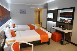 アスワンにあるNile Plaza Suitesのベッド2台、机、テレビのある寝室