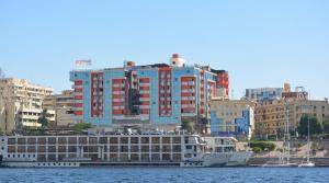 アスワンにあるNile Plaza Suitesの大きな建物の隣の水に浮かぶ大きなボート