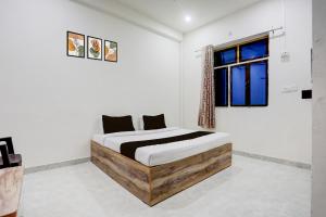 Schlafzimmer mit einem Bett mit einem Holzrahmen und einem Fenster in der Unterkunft Hotel O Kashi Home in Kakarmatha