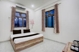 ein Schlafzimmer mit einem Bett und zwei Fenstern in der Unterkunft Hotel O Kashi Home in Kakarmatha