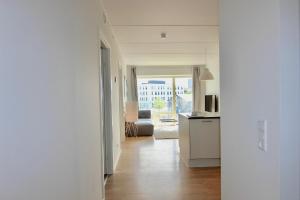 Pasillo blanco con cocina y sala de estar en Beautiful 2-BR w a balcony by Odense Harbour - 125, en Odense