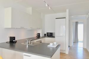 cocina blanca con fregadero y encimera en Beautiful 2-BR w a balcony by Odense Harbour - 125, en Odense