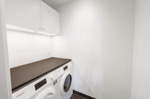 eine Waschmaschine und ein Trockner in einer weißen Waschküche in der Unterkunft Beautful 2-BR in DGBN Silver property - 315 in Hunderup