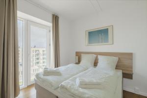 ein weißes Bett in einem Zimmer mit einem großen Fenster in der Unterkunft Beautful 2-BR in DGBN Silver property - 315 in Hunderup