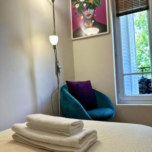 a room with a bed with a lamp and a blue chair at Cosy & Lumineux 6 min PARIS La Défense PARKING 5 pers in Suresnes