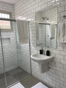 a white bathroom with a sink and a mirror at Casa da Árvore Bertioga in Bertioga +63 photos