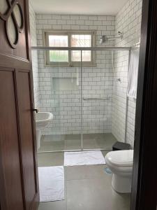a bathroom with a glass shower and a toilet at Casa da Árvore Bertioga in Bertioga