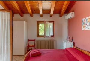 a bedroom with a red bed and a window at Alloggio agrituristico Zambon in Vedelago