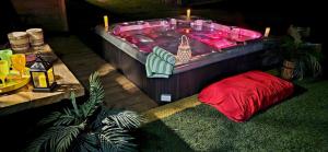 una vasca idromassaggio con un cuscino rosso accanto a un tavolo di Domaine pour 21 pers avec SPA et GRANGE Festive a Saint-Justin