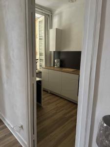 a kitchen with white cabinets and a wooden floor at Studio 2 personnes in La Bourboule