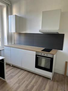 a kitchen with white cabinets and a stove top oven at Studio 2 personnes in La Bourboule