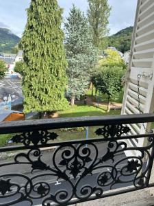 a balcony with a wrought iron railing and a tree at Studio 2 personnes in La Bourboule