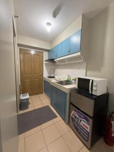 a kitchen with blue cabinets and a sink and a microwave at Standard Room at 8 Spatial by Forever-mc Condotel 8335 in Davao City
