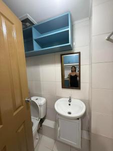 a woman taking a picture of a bathroom with a sink at Standard Room at 8 Spatial by Forever-mc Condotel 8335 in Davao City +8 photos