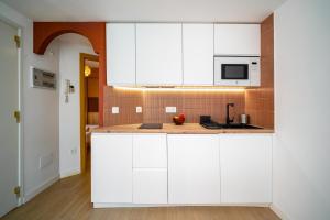 a kitchen with white cabinets and a microwave at TrendyHomes Laguna Beach in Vera