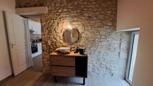 a bathroom with a vanity and a mirror on a stone wall at Spacieuse maison de vacances in Sorges