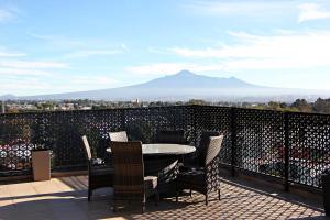 a table and chairs on a balcony with a view of a mountain at Penthouse with Glass Floor and Volcano View in Cholula