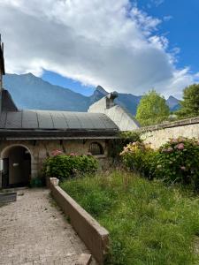 un antiguo edificio de piedra con montañas en el fondo en La Douceur du Fort - Parking, extérieur, vue, en Mercury