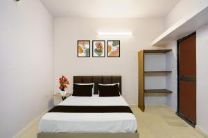 1 dormitorio con 1 cama grande con sábanas blancas y negras en Hotel O Agrawal Inn, en Jabalpur