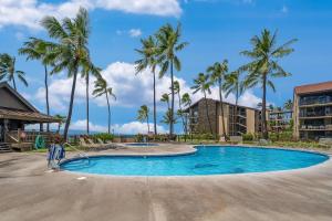 a swimming pool with palm trees in a resort at Papakea L101 · PK L101 Maui Ground-Floor Condo with Ocean Views in Honokowai
