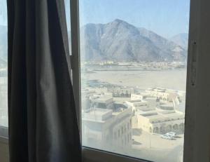 a window with a view of a city and mountains at Stay home in ‘Uqayr