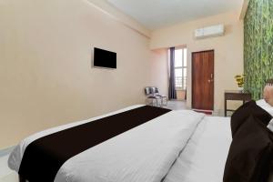 Un dormitorio con una cama y un televisor en la pared. en Hotel O by OYO Swastik inn, en Gwalior