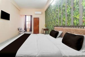 Un dormitorio con una cama grande y una pared con plantas. en Hotel O by OYO Swastik inn, en Gwalior