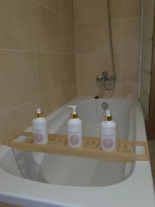 a bathroom with three soap bottles on a wooden shelf in a bath tub at Ático Formoso in Cee +9 photos