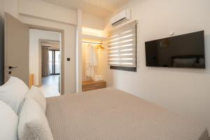 a bedroom with a bed and a flat screen tv at Paizan Homes - Kos City Center Apartments in Kos