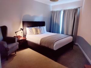 a bedroom with a bed with a chair and a window at Michelangelos - Rooms, Restaurant & Bar in Gateshead