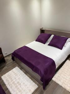 a bedroom with a bed with purple sheets and rugs at Casa Maria in Bezons