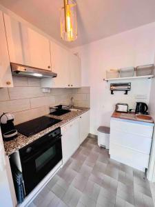 cocina con armarios blancos y fogones negros en L'Eden Apt 4 Prs, clim, parking, 300 m des plages, en Antibes