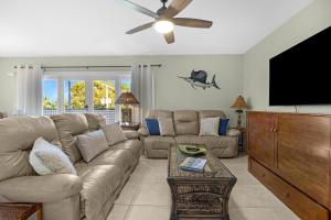 een woonkamer met een bank en een flatscreen-tv bij Coastline Comfort in Key West