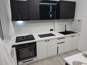 a white kitchen with a stove and a sink at Apartament de Vacanță Straja in Lupeni