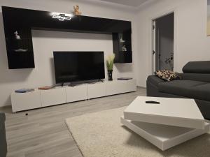 a living room with a flat screen tv on a white cabinet at Apartament de Vacanță Straja in Lupeni