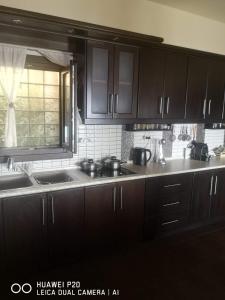 een keuken met zwarte kasten, een gootsteen en een raam bij Holiday house afetes in Afétai +46 foto's