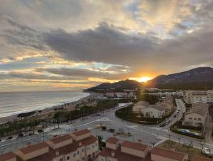 Apartamento con terraza, vistas playa y montaña في هوسبيتاليت دي لانفنت: اطلالة على المدينة والمحيط وقت الغروب