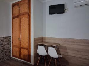 a room with two white chairs and a table and a television at Hostal La Pastora in Candeleda