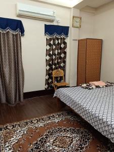 Schlafzimmer mit einem Bett, einem Teppich und Vorhängen in der Unterkunft 1st floor room in Kalkutta