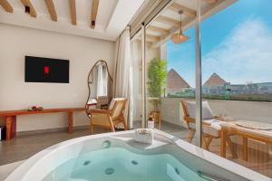 Una bañera en una habitación con una ventana grande. en ONE GATE Pyramids View INN, en El Cairo